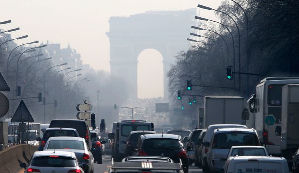 Pollution trafic embouteillage voitures paris rush hour traffic fills an avenue leading up to the arc de triomphe which seen through a small particle haze at neuilly sur seine